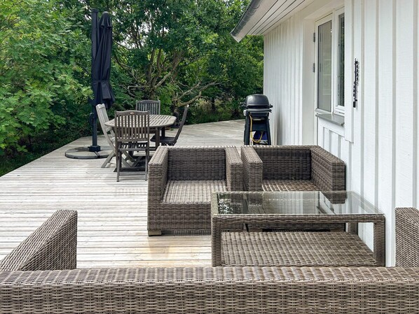 A deck with wicker furniture, including a sofa and chairs, and a table.