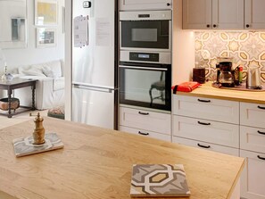 A modern kitchen with white cabinetry, a wooden countertop, and a built-in oven.