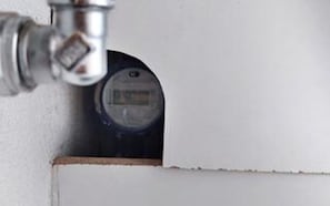 A corner of a room with a white wall and a visible plumbing fixture.