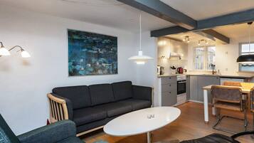 Uma sala de estar moderna com um sofá, uma mesa de centro e um espaço de jantar com mesa e cadeiras.