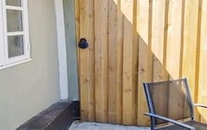 A wooden gate, a window, and a metal chair.