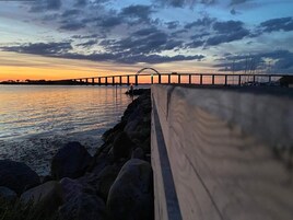 Vista al atardecer de un puente sobre el agua, con un paseo de madera a lo largo de la orilla.
