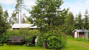A grassy outdoor area with a wooden bench, a small table, and a shed. - 7 Person Holiday Home in Hova (Hova)