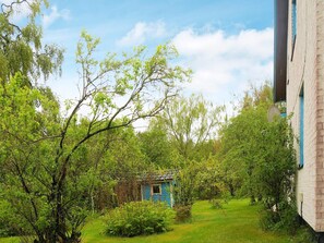 Une petite maison bleue, entourée d’une végétation luxuriante et d’arbres.