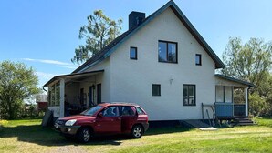 A two-story house with a covered porch and a red car parked in front. - 7 Person Holiday Home in Hova (Hova)