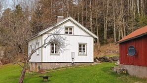 Une maison blanche avec une grange rouge, entourée d’arbres et d’une zone herbeuse.