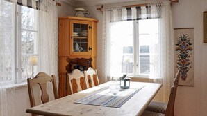 Une salle à manger avec une table en bois, six chaises, un buffet contenant de la vaisselle et un élément décoratif mural.
