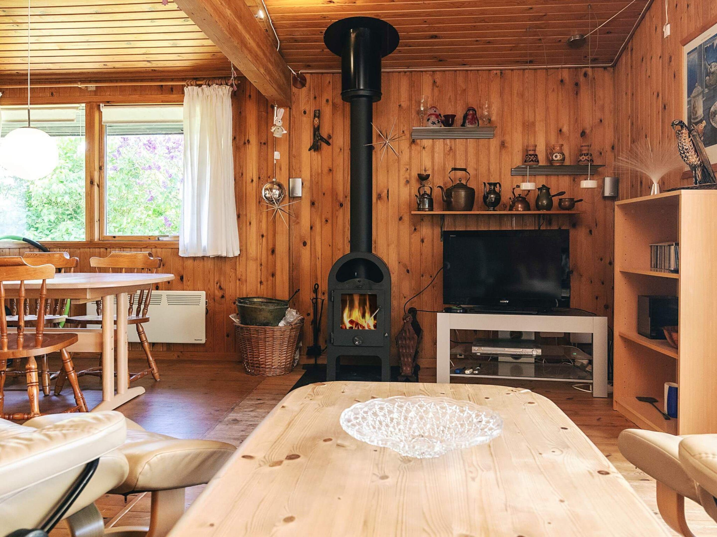 A cozy cabin interior with a fireplace, wooden walls, a dining area, and a television.