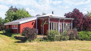 Une maison en bois rouge, avec un toit en pente et un porche abrité.