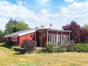 A red wooden house with a sloped roof and a covered porch. - 5 Person Holiday Home in Bogo By (Bogø By)