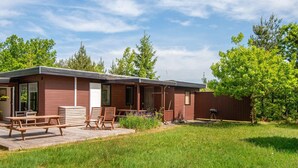 Een gelijkvloers houten vakantiehuisje met een terras, een barbecue en een omheinde tuin.