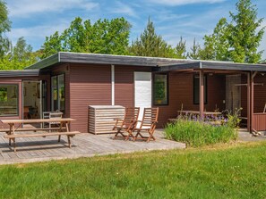Une cabane en bois dotée d’une terrasse, d’un espace salon extérieur et d’un jardin.