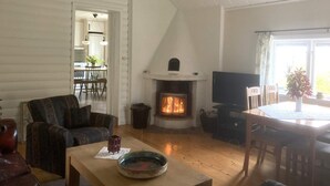 A cozy living room with a fireplace, a television, and a dining area with a table and chairs. - 6 Person Holiday Home in Boxholm-by Traum (Boxholm)