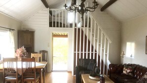 A spacious living room with a wooden floor, a dining area with a table and chairs, a sofa, and a staircase with white railings. - 6 Person Holiday Home in Boxholm-by Traum (Boxholm)