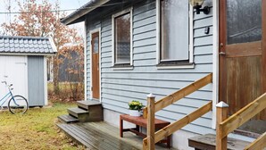 A two-story house with a wooden staircase leading to a front door, a small porch with a bench, and a bicycle parked outside. - 4 Person Holiday Home in Heberg (Heberg)
