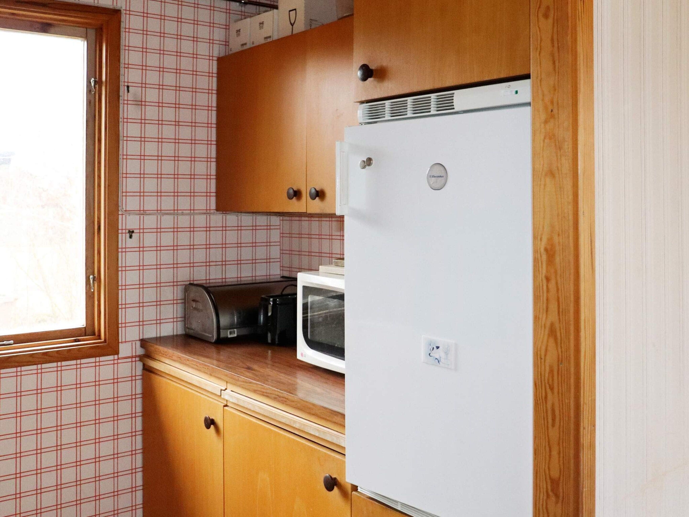 Une cuisine compacte avec des meubles en bois, un réfrigérateur blanc, un grille-pain et un four à micro-ondes.