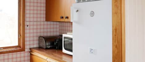 Une cuisine compacte avec des meubles en bois, un réfrigérateur blanc, un grille-pain et un four à micro-ondes.