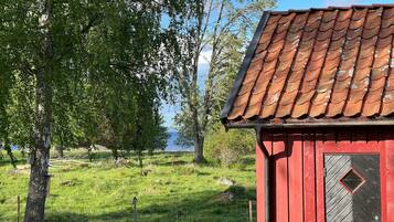 A red wooden building with a tiled roof, surrounded by grass and trees.
