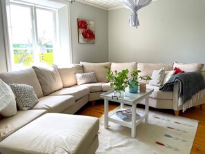 A living room with a sectional sofa, a coffee table, and a plant.