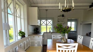 Une cuisine avec des meubles blancs, une table à manger en bois et un banc avec des coussins.