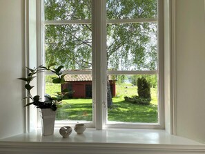 A window with a view of a green landscape and a building with a red roof.