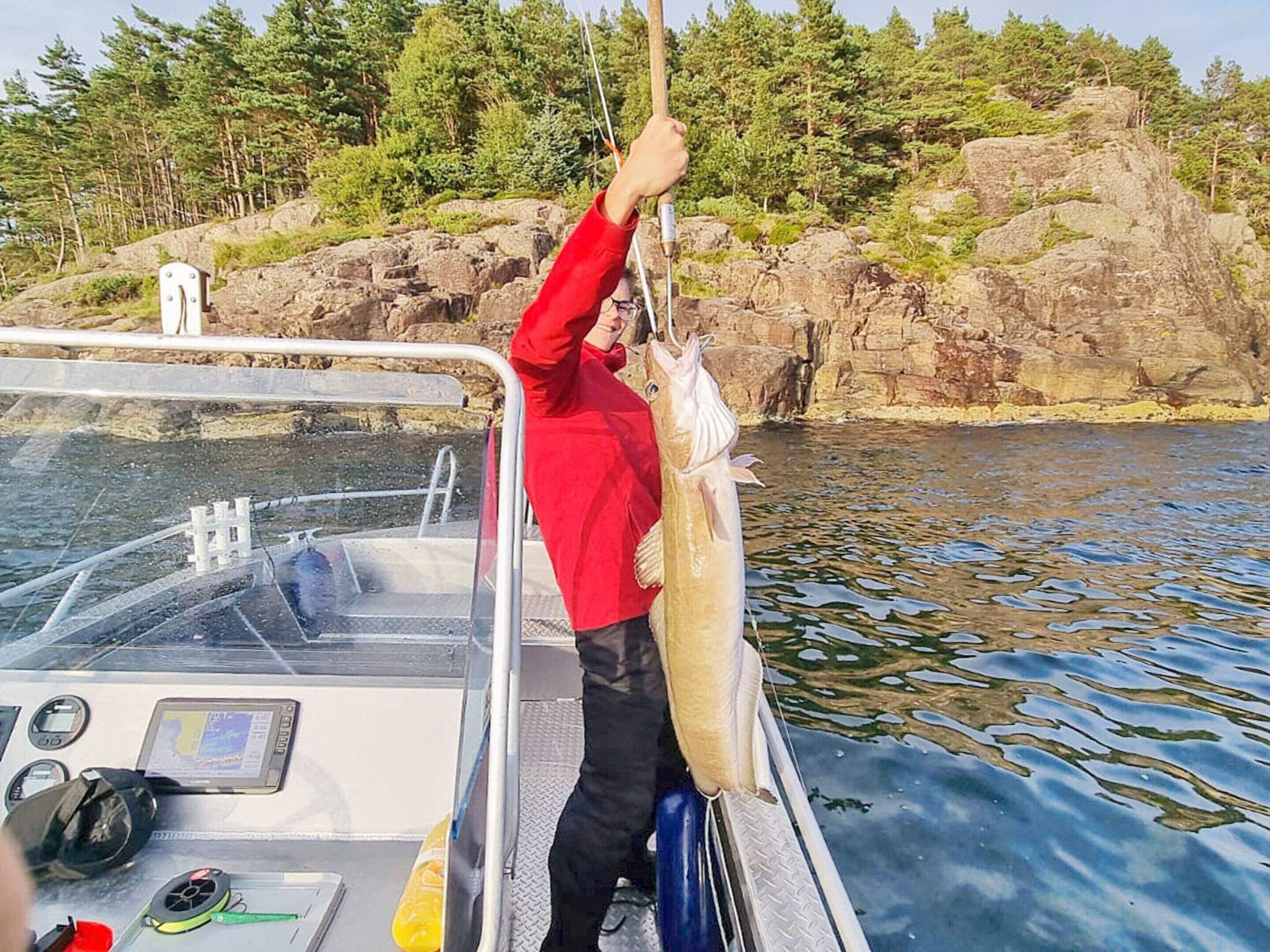 A person on a boat holding a large fish.