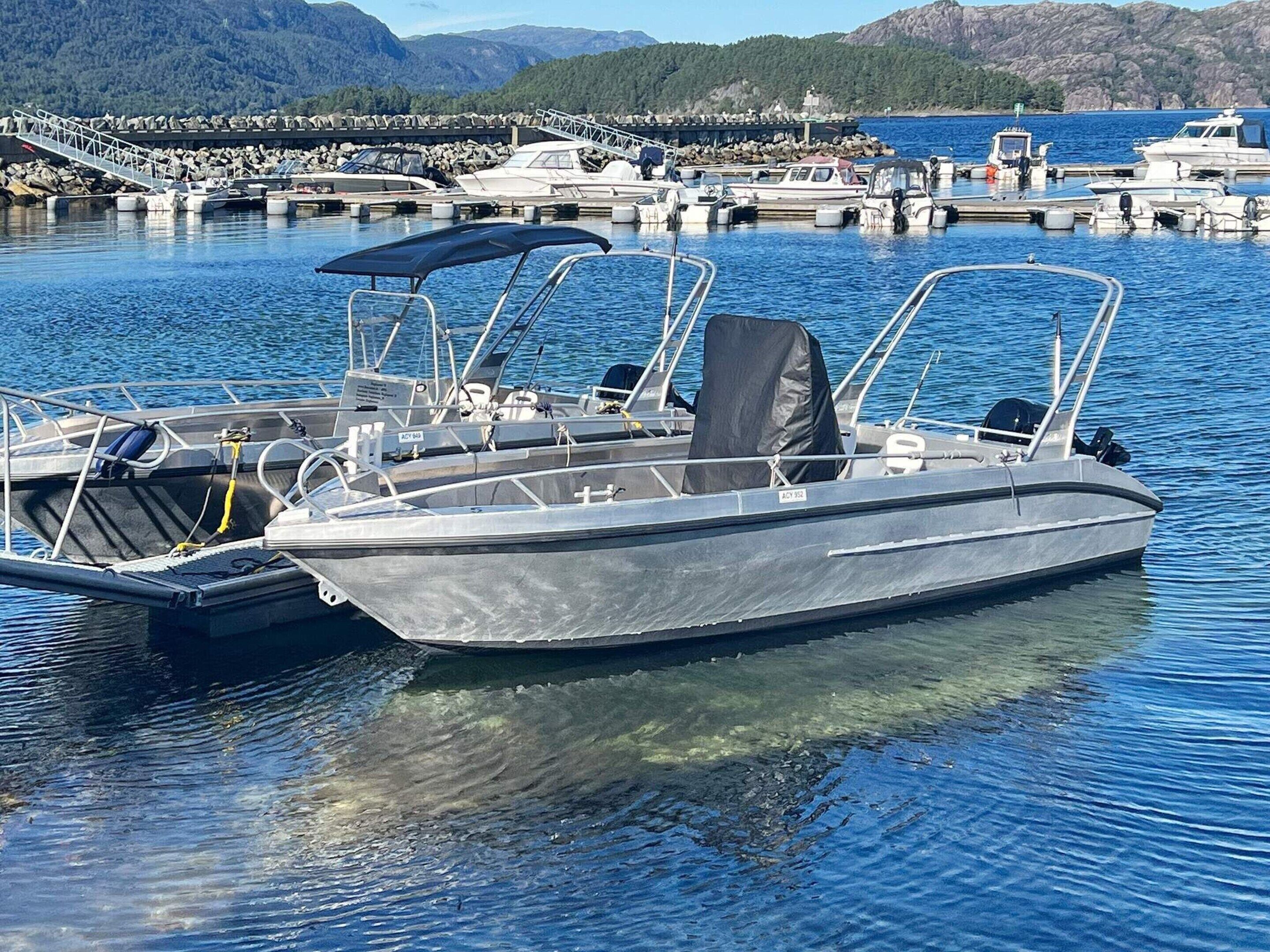 A motorboat docked at a marina with a clear view of the surrounding rocky landscape and mountains.