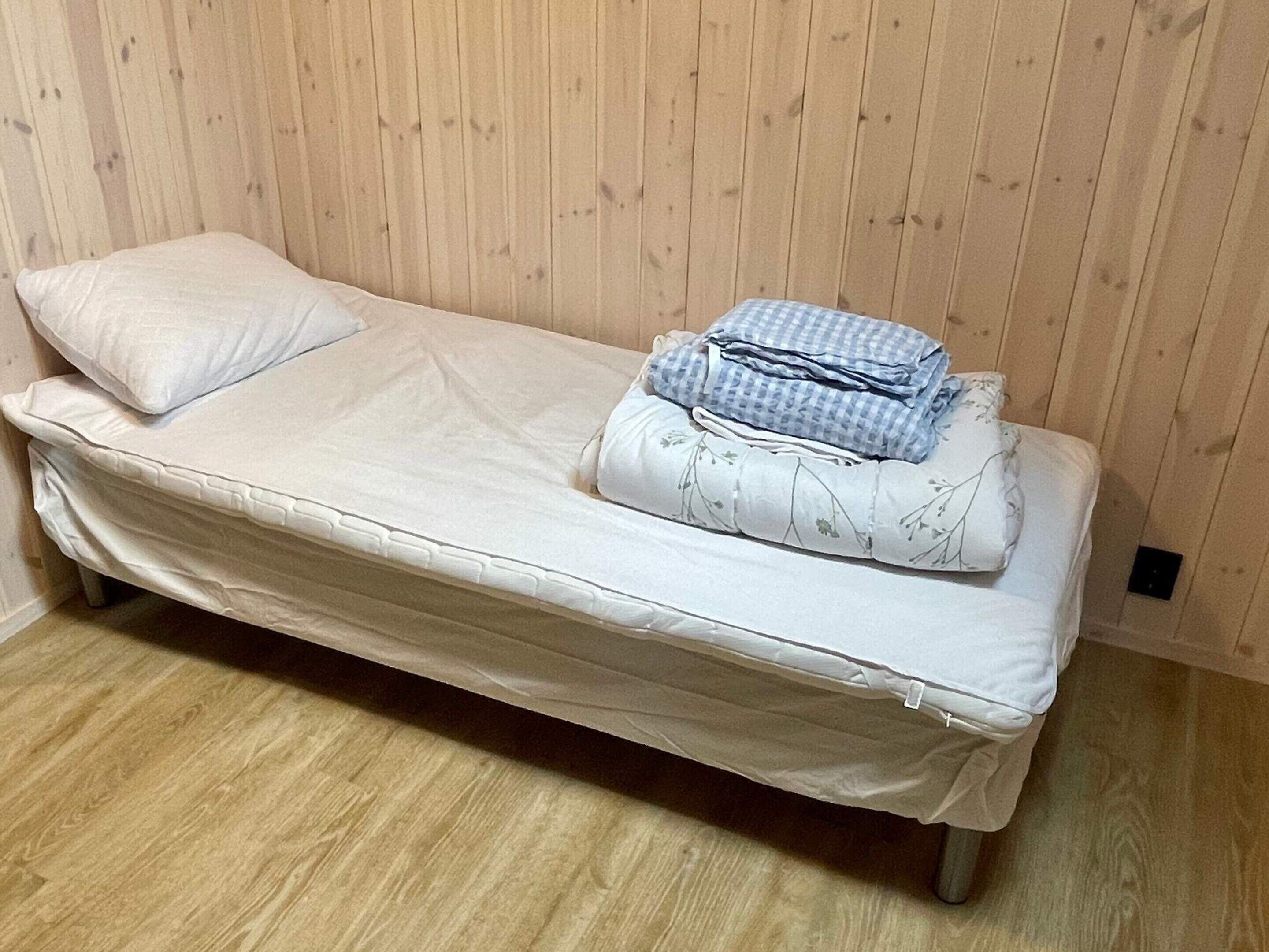 Un letto singolo con coprimaterasso, cuscini e coperte piegate.