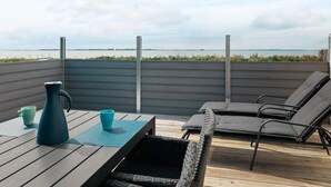A wooden deck with a table, two chairs, and a vase.