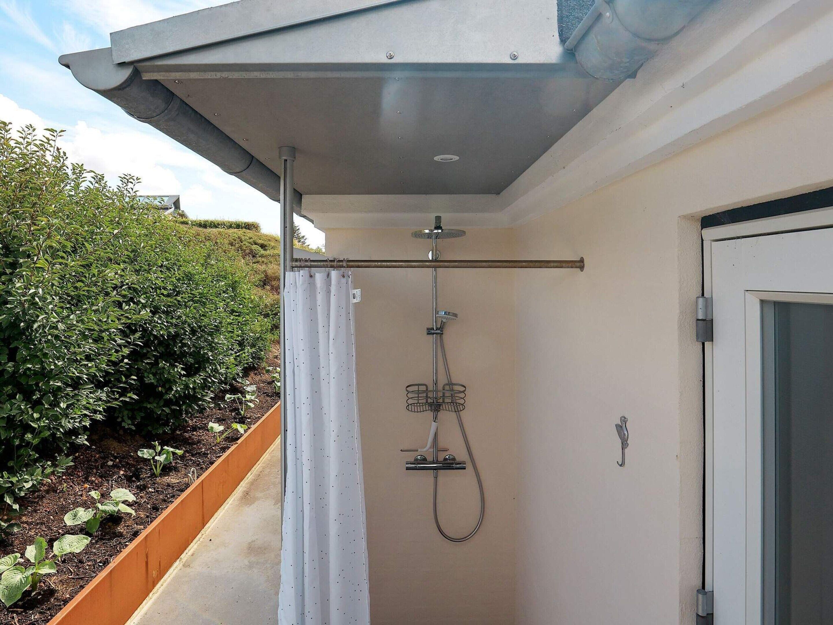 A compact, modern shower area with a metal showerhead and hose, adjacent to a door.