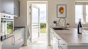 A modern kitchen with a large island, a coffee machine, and a wine bottle.