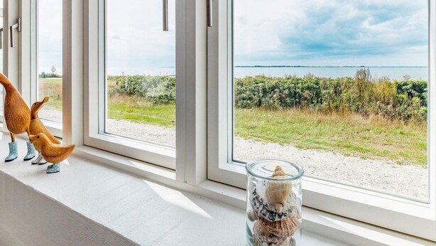 A view through a window with a glass jar containing seashells.