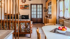 Una habitación acogedora con una cama, una mesa de comedor con fruta, una estantería y un techo de madera.