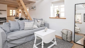 A modern living room with a grey sofa, white coffee table, and a wooden ladder. - 4 Person Holiday Home in Saeby (Sæby)