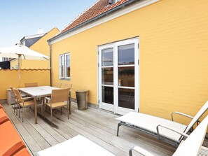 A yellow building with a large window, a table with chairs, and a covered outdoor area. - 5 Star Holiday Home in Skagen (Skagen)