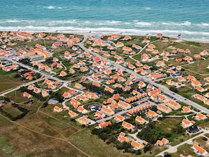 An aerial view of a coastal residential area with houses having orange roofs, arranged in a grid pattern, and a road running through the center. - 5 Star Holiday Home in Skagen (Skagen)