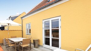 A yellow building with a large window, a table with chairs, and a covered outdoor area. - 5 Star Holiday Home in Skagen (Skagen)