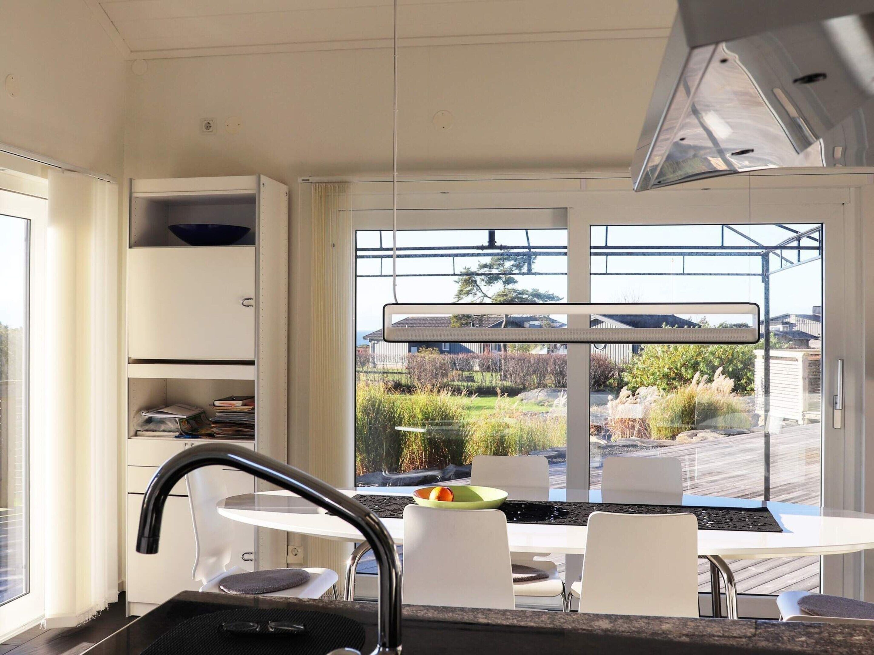 A modern kitchen with white cabinets, a black faucet, and a dining area with a table and chairs.
