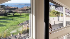 A room with a large window overlooking a grassy area with rocks and a view of the sea. - 10 Person Holiday Home in Bua (Bua)