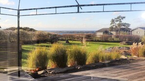 A wooden deck with a view of a landscaped garden and distant buildings. - 10 Person Holiday Home in Bua (Bua)