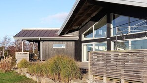 A modern house with a sloped roof, large windows, and a wooden deck. - 10 Person Holiday Home in Bua (Bua)