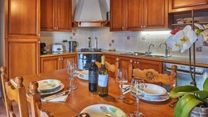 A wooden kitchen with a dining table set for a meal, featuring wine glasses and plates. - Casa Rosy by Interhome (Porlezza)