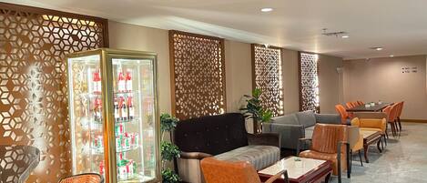 A hotel lobby with seating areas, a beverage refrigerator, decorative panels, and a clear floor plan.