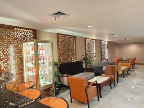 Un hall de hotel con zonas de estar, un refrigerador para bebidas, paneles decorativos y un plano de distribución visible.
