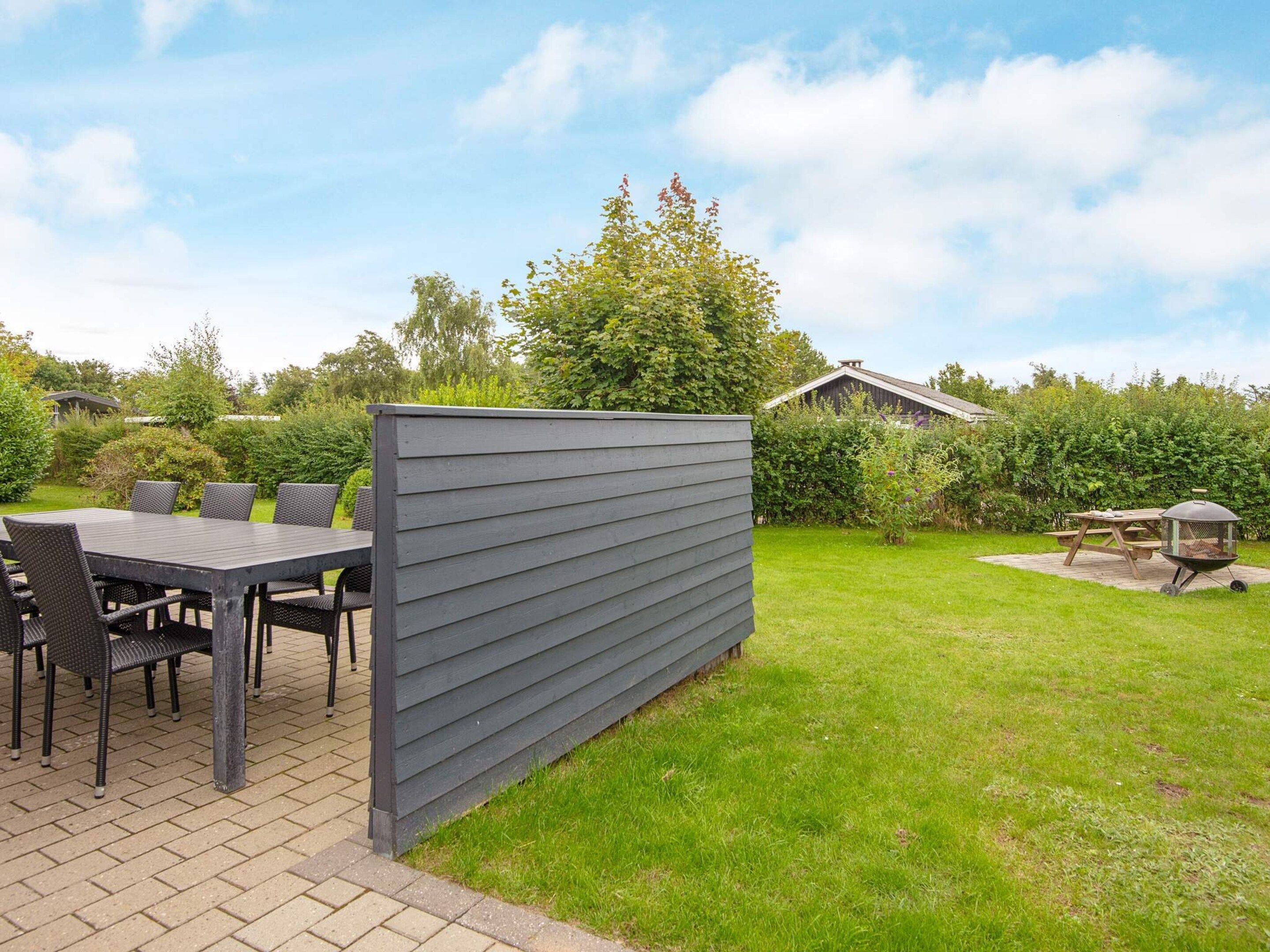Une terrasse extérieure avec une table et des chaises, un barbecue et un écran pour préserver l’intimité.