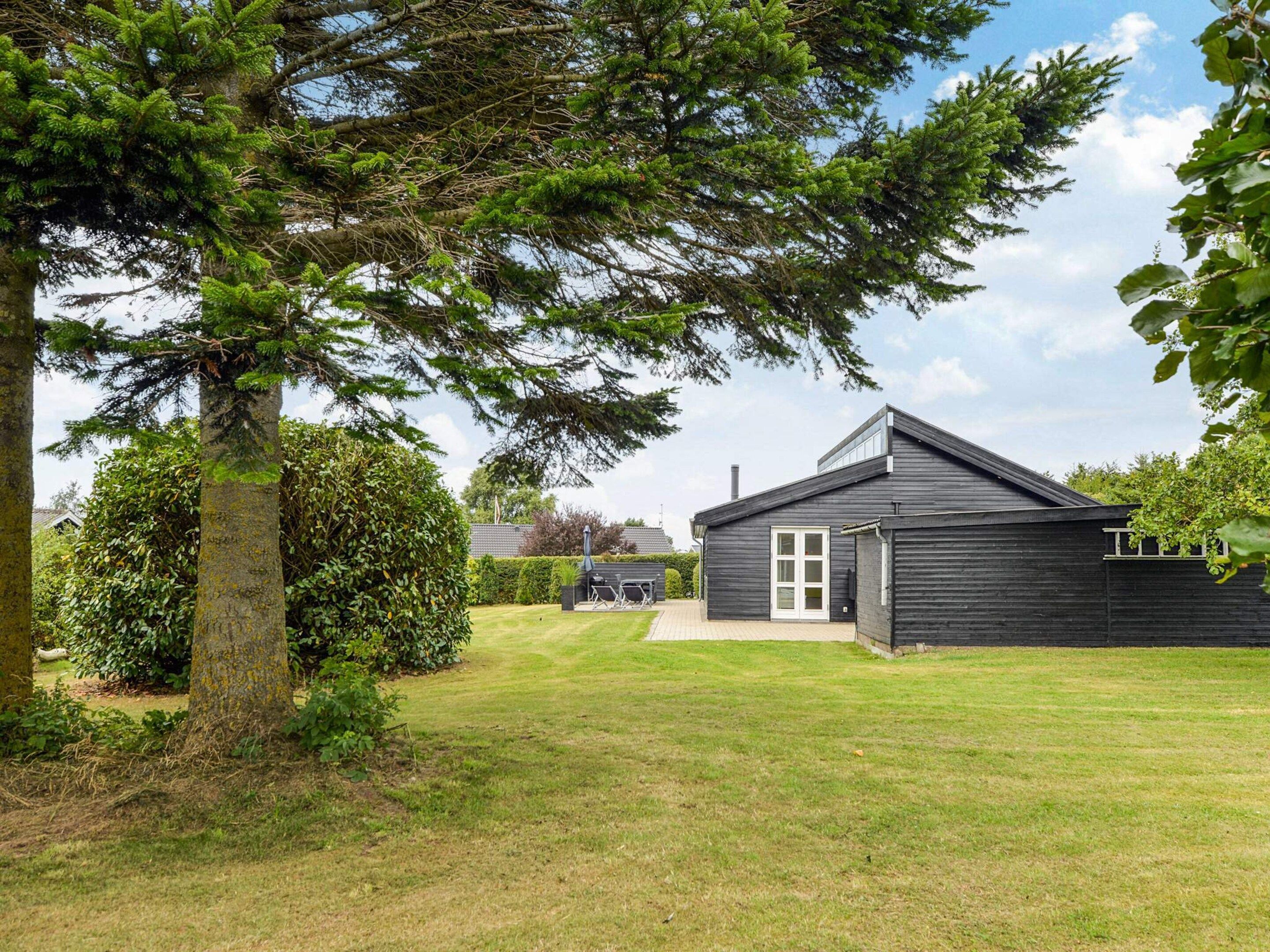 A modern house with a dark exterior, a visible garage, and a well-maintained lawn.
