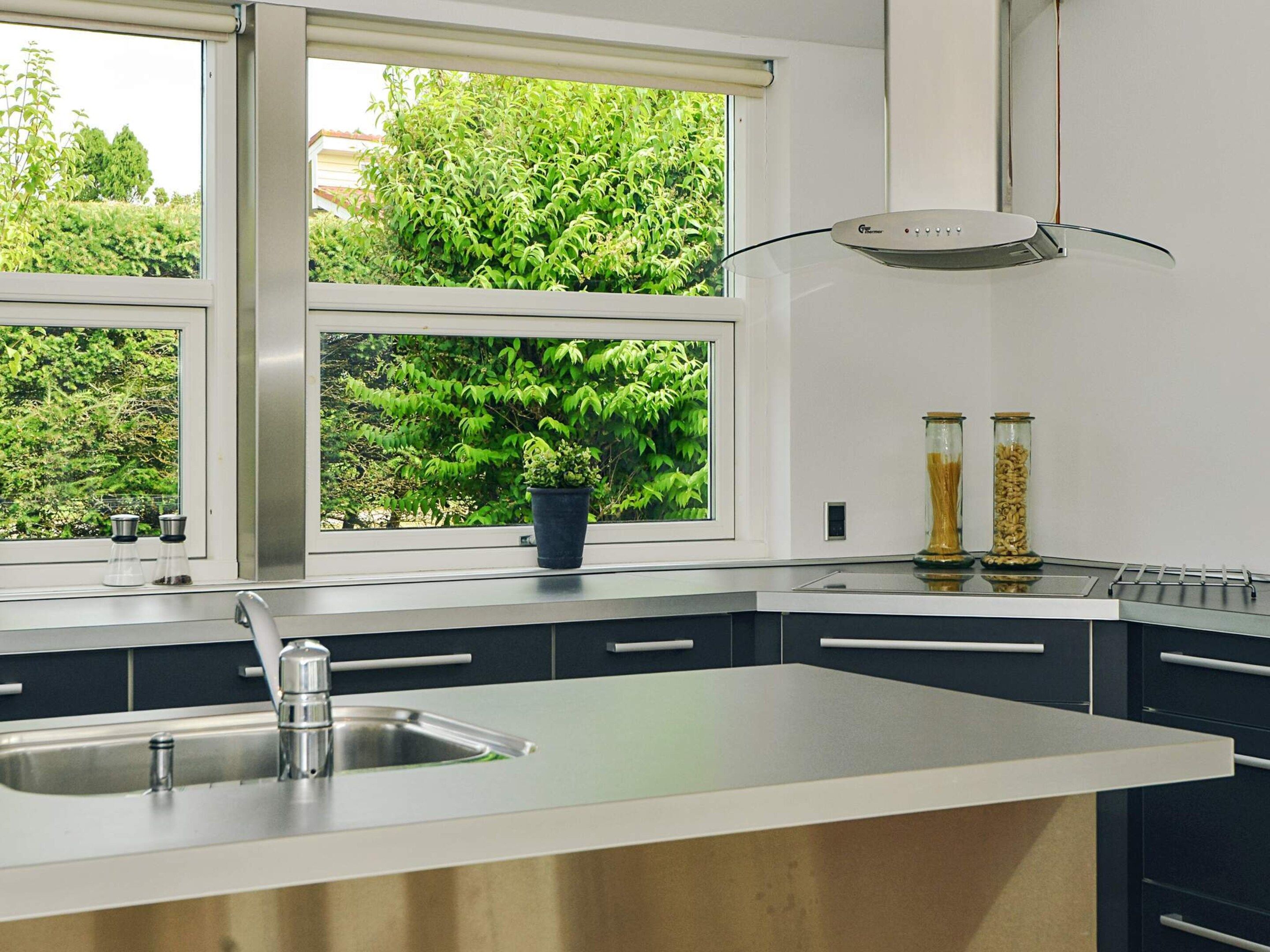 Eine moderne Küche mit einem großen Fenster, einer Spüle und zwei Gewürzbehältern auf der Arbeitsfläche.