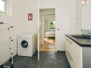 Ett kompakt och modernt kök med en inbyggd diskho, en tvättmaskin och ett torkställ.