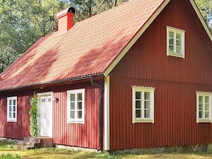 A red wooden house with a sloped roof, a chimney, and two windows with white frames. - 7 Person Holiday Home in Vankiva (Vankiva)