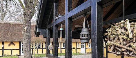 A traditional building with a thatched roof, wooden beams, and a hanging bell.